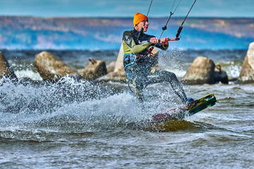 A male kiter slides on the surface of the water. Splashes of water fly apart. Close-up.