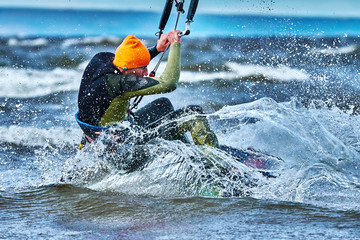A male kiter slides on the surface of the water. Splashes of water fly apart. Close-up.