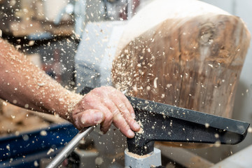 carpenter forms rotating wood with turnery and flying timber saw dust