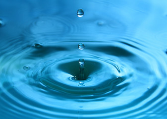 A drop of water is falling. Abstract blue background.