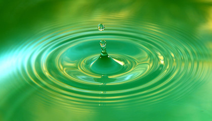 A drop of water is falling. Abstract green background.