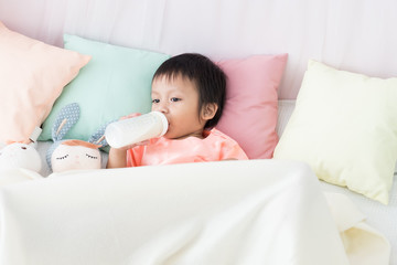 Obraz na płótnie Canvas Lovely toddler boy lie down in bed with milk bottle