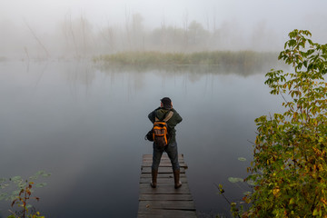 tourist views and photographs from the wooden bridge an autumn fog on the river.