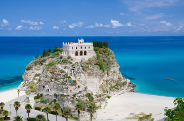Monastery Sanctuary church of Santa Maria dell Isola on top of rock Tyrrhenian Sea and green palm trees, blue sky white clouds in summer clear day, Tropea town, Vibo Valentia, Calabria, Southern Italy - obrazy, fototapety, plakaty