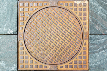 Old rusty sewer hatch on an old metal plate. View from above.