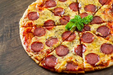 Pepperoni Pizza with Mozzarella cheese, salami, Tomato sauce, pepper, Spices and Fresh Basil. Italian pizza on wooden background