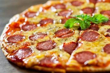 Pepperoni Pizza with Mozzarella cheese, salami, Tomato sauce, pepper, Spices and Fresh Basil. Italian pizza on wooden background