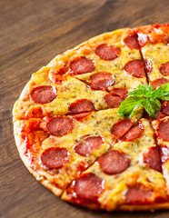 Pepperoni Pizza with Mozzarella cheese, salami, Tomato sauce, pepper, Spices and Fresh Basil. Italian pizza on wooden background