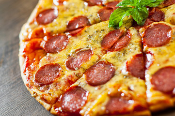 Pepperoni Pizza with Mozzarella cheese, salami, Tomato sauce, pepper, Spices and Fresh Basil. Italian pizza on wooden background