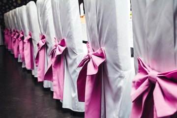 large pink bows on chairs in white covers - wedding banquet details