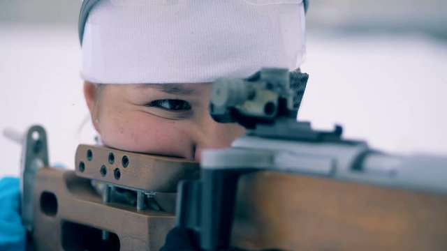 One woman stands and aims with a sports rifle, while competing. 4K