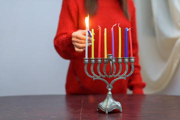 Jewish Woman lighting Hanukkah Candles in a menorah. People celebrate Chanukah by lighting candles...
