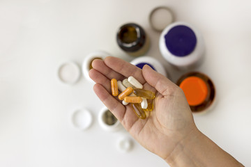 Hand with different set of pills with cotainers of drugs on the background. Top view