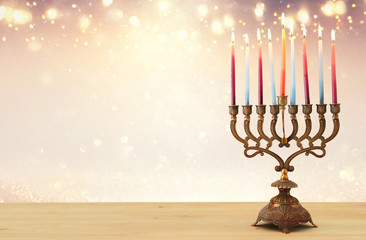 image of jewish holiday Hanukkah background with menorah (traditional candelabra) and candles over glitter shiny background. © tomertu