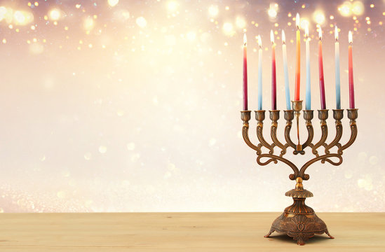 image of jewish holiday Hanukkah background with menorah (traditional candelabra) and candles over glitter shiny background.
