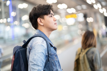 Young Asian caucasian man moving up on an escalator at the airport and looked toward the forward....