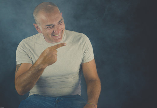 A man, 50Y old, is showing the index of the right hand. Black background. Smoke