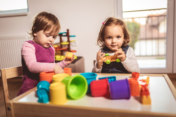 Children toddlers girls play toys at home, kindergarten or nursery.