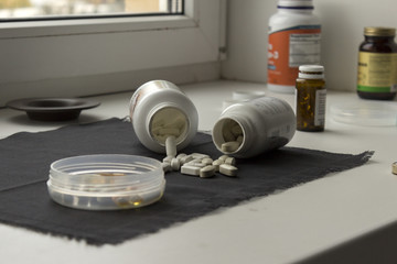 Containers of different medicine on the table. Lots of different pills