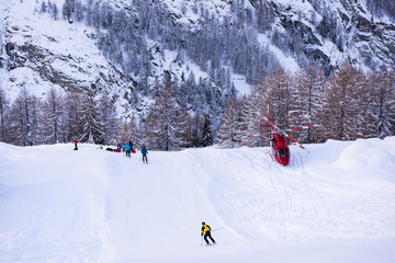 rescue team with a red helicopter rescuing a hurt skier