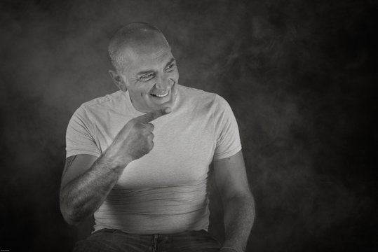 A man, 50Y old, is showing the index of the right hand. Black background. Smoke