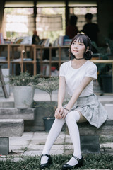 portrait of asian girl with white shirt and skirt looking in outdoor nature vintage film style