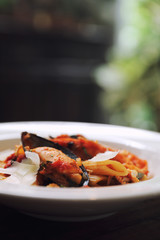 Penne pasta tomato sauce arabiata with seafood on wood background vintage style