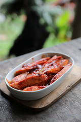 Traditional German currywurst pieces of sausage with curry sauce on wood background