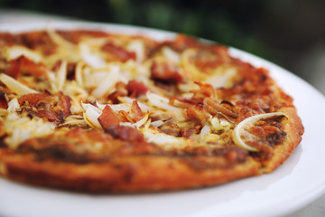 Pizza with crispy bacon onion on outdoor table