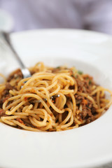 spaghetti Bolognese with minced beef and tomato sauce garnished with parmesan cheese and basil , Italian food