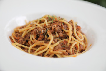 spaghetti Bolognese with minced beef and tomato sauce garnished with parmesan cheese and basil , Italian food