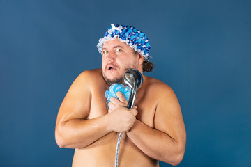 Funny fat man in blue cap sing in the shower