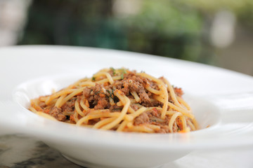 spaghetti Bolognese with minced beef and tomato sauce garnished with parmesan cheese and basil , Italian food