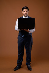 Young handsome Iranian businessman against brown background