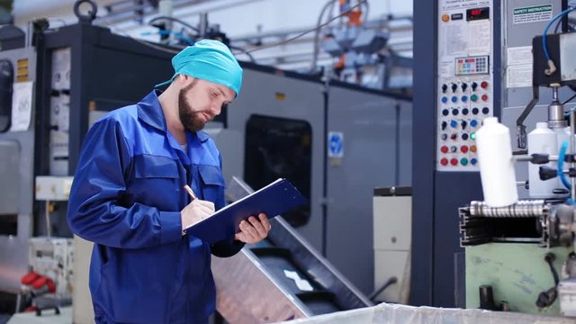Worker with clipboard near machinery in factory