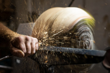 flying wood shavings while cutting and carving wooden bowl on turnery machine