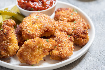 Fried crispy chicken nuggets with ketchup and pickles