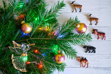 Decorated with toys and lights, a branch of the Christmas tree next to the animals of Eurasia and the angel. New Year in Eurasia.