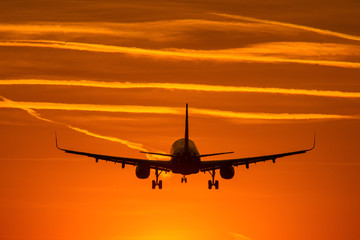Fototapeta na wymiar Airplane prepare for landing at sunset with beautiful red sky in background