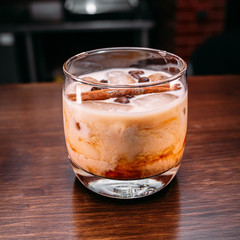 a glass of beautiful bright cocktail on a wooden surface decorated with fruits, berries, leaf of mint and basil at bar counter background