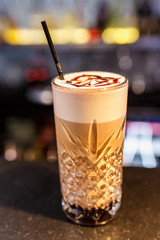 a glass of beautiful bright cocktail on a wooden surface decorated with fruits, berries, leaf of mint and basil at bar counter background