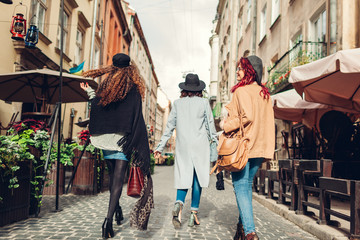 Fototapeta na wymiar Outdoor shot of three young women walking on city street. Girls having fun. Back view
