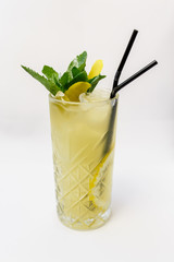 a glass of beautiful bright cocktail on a wooden surface decorated with fruits, berries, leaf of mint and basil at bar counter background