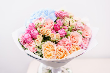 beautiful spring bouquet. flowers arrangement with various of colors in glass vase on pink table. bright room, white wall.