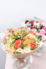 two beautiful spring bouquet. flowers arrangements with various of colors in glass vase on pink table. bright room, white wall
