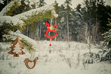 Wooden Christmas decoration on branch of pine among the winter forest. Christmas and happy New year concept