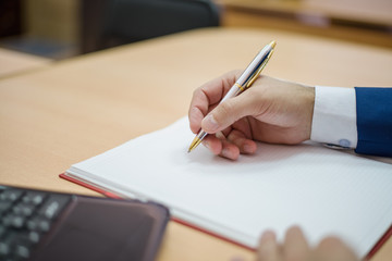 a man holding a pen, a businessman writes on paper, a businessman in a suit holding a pen