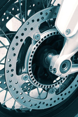 Front brake discs and wheel on a motorbike with blue toning