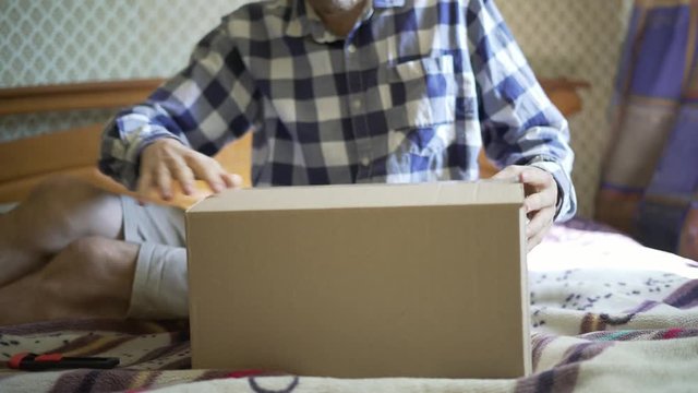 hands using knife to open the delivered package  at home