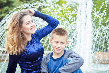 Happy beautiful mother and son enjoying near the fountain